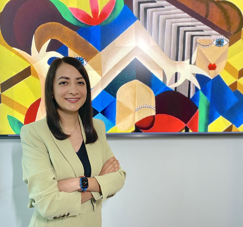 Bahar Asgari standing in front of one of her brightly colored abstract art pieces