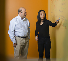 a man and woman working in front of a white board