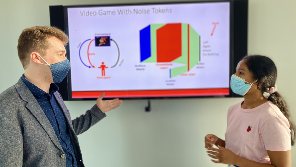 A man and woman pointing to a whiteboard 