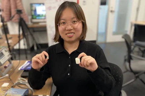 Yang Bai holds two sensor devices used for ambient sensing applications.