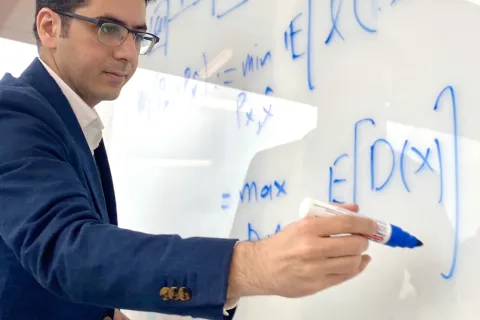 Feizi writing equations on white board.