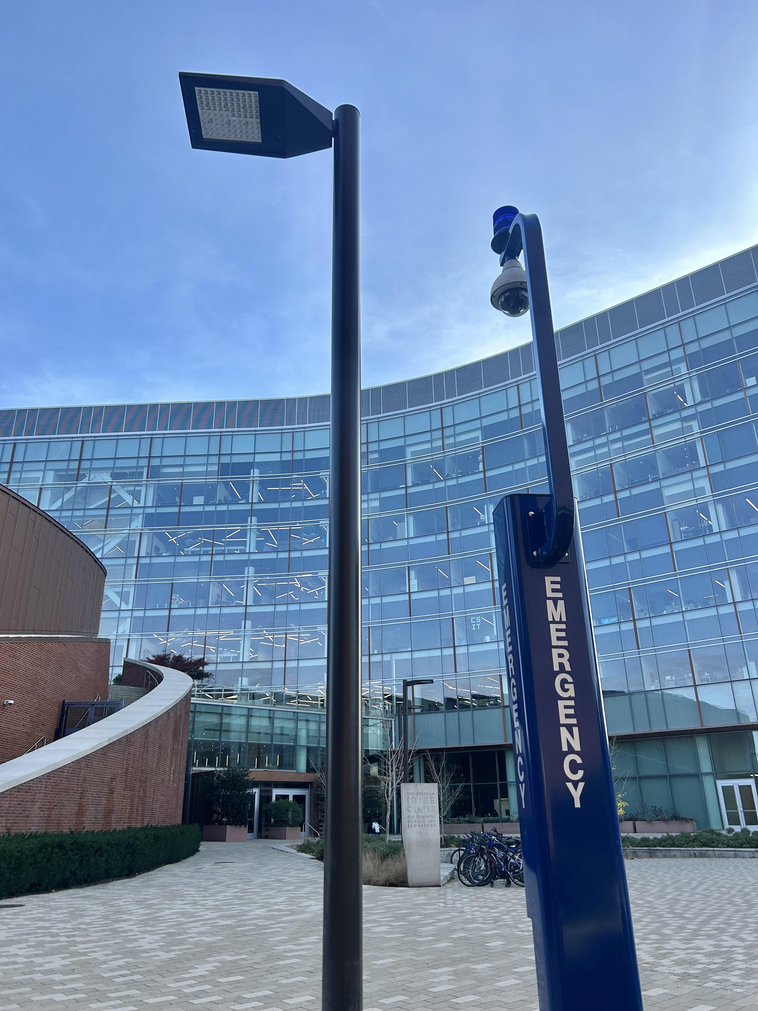 blue emergency call box in front of glass building