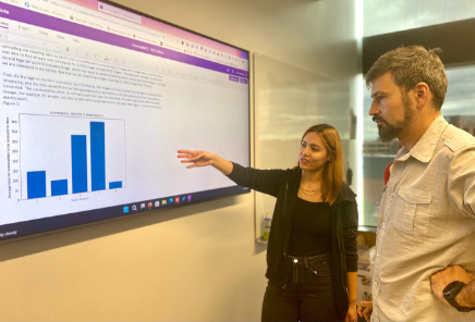 A man and woman pointing at a screen