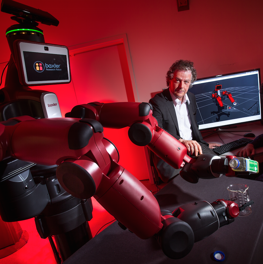 Yiannis Aloimonos sits with a Baxter Research Robot next to him. 