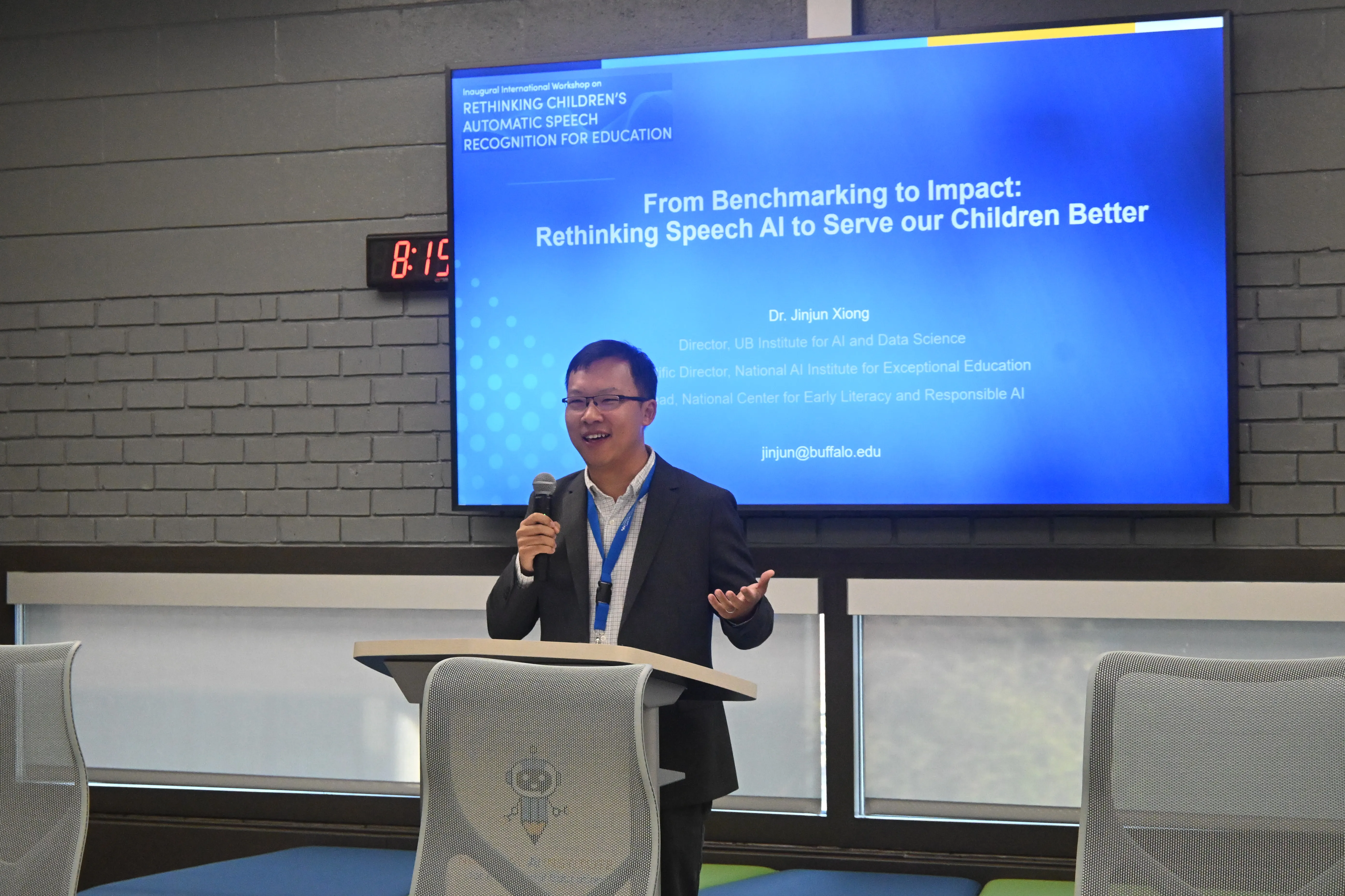 Jing Liu gives a presentation in front of a blue screen.